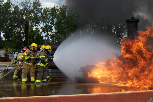 "In-house" Fire Training with firefighters working a hose on a controlled fire